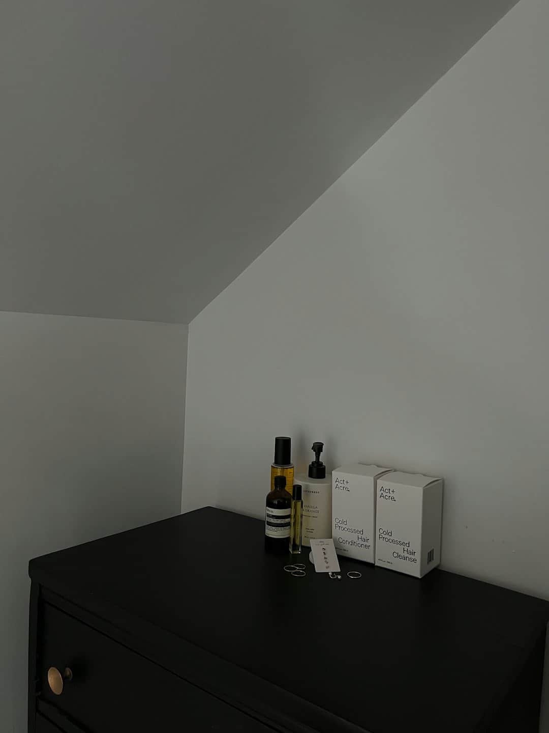 Personal care products arranged on a dark wooden dresser.